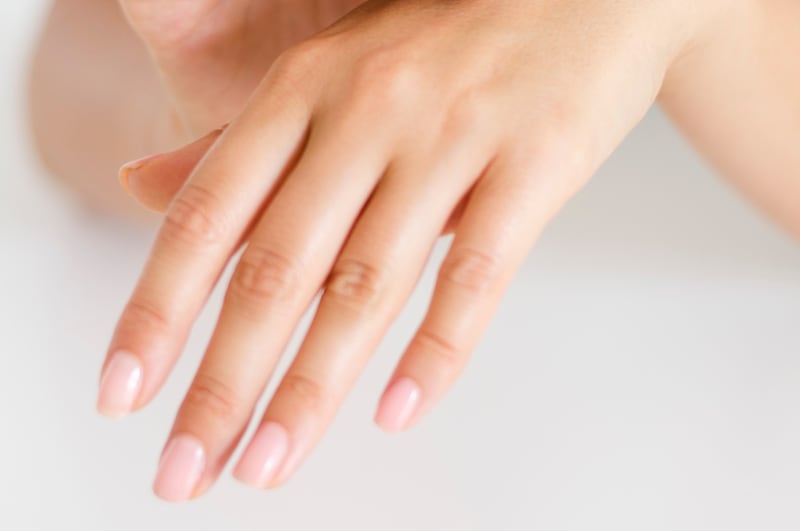 Primer plano de un par de manos femeninas, con uñas pintadas de color rosa.