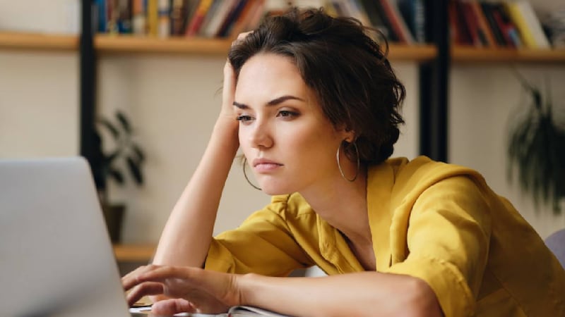 Mujer con blusa amarilla frente a una computadora.