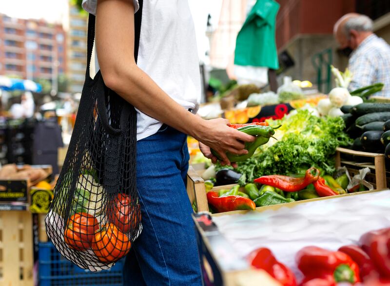 Mujer en el mercado cargando bolsa de red negra.